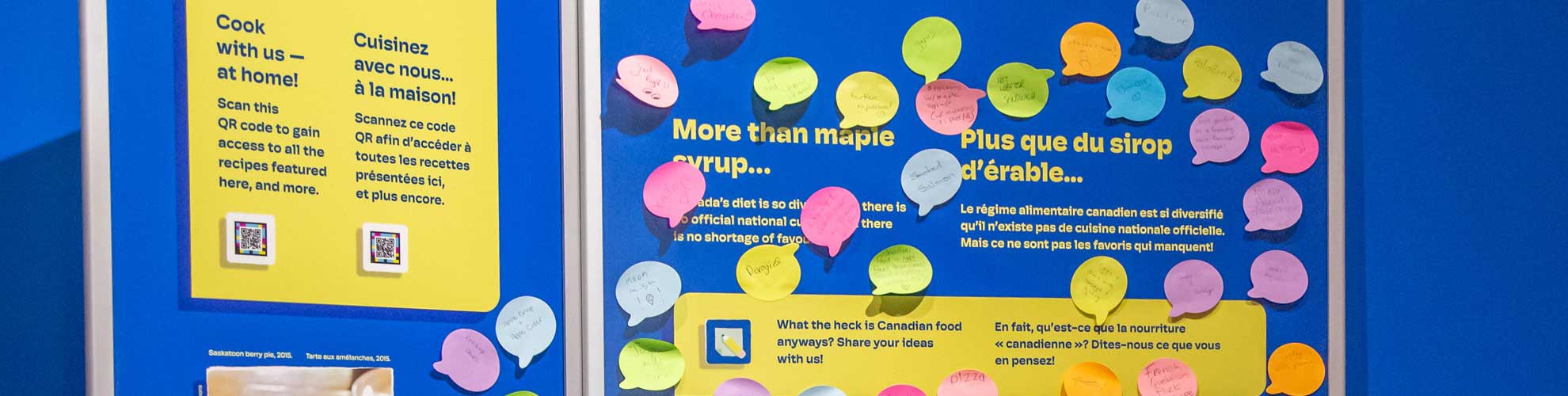 Un panneau d’exposition recouvert de papiers adhésifs colorés répondant à la question : Qu’est-ce que la cuisine canadienne?