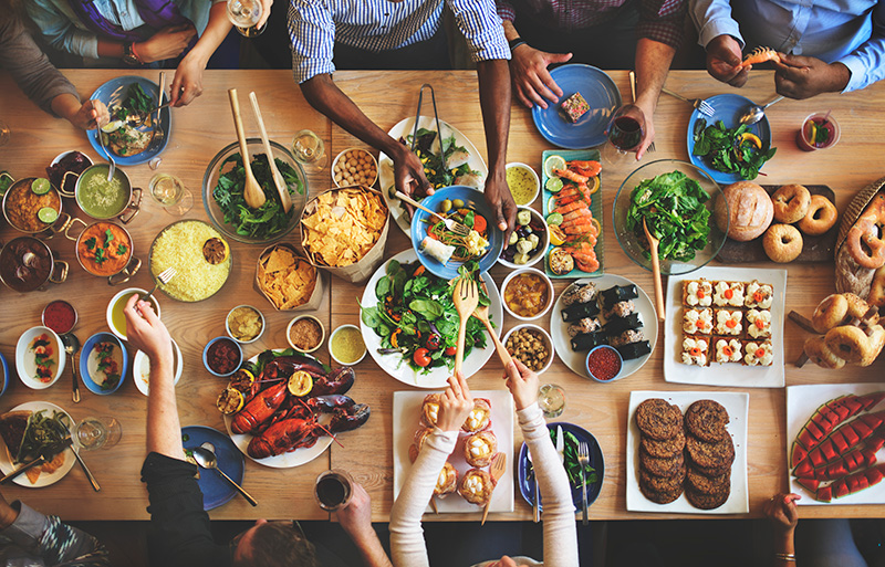  Du curry, du riz, des fruits de mer, des salades et des pains de différentes cultures sont disposés sur une grande table.