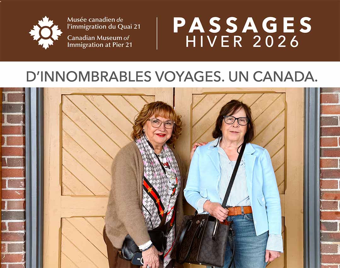 Deux femmes à la peau pâle, âgées d’une soixantaine d’années, posent devant une paire de portes en bois.