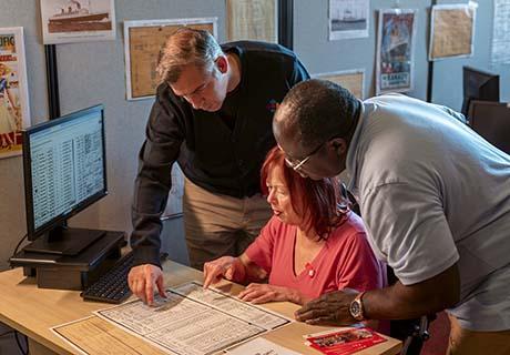 Trois visiteurs consultent les registres d'immigration.