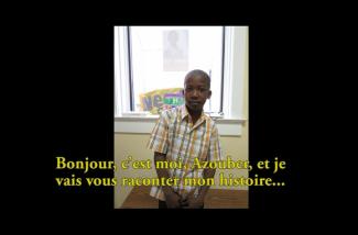 Un jeune garçon en chemise à carreaux se tient devant une fenêtre.