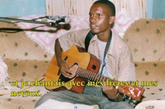 Un jeune homme joue de la guitare et chante dans un microphone.