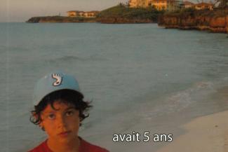 Un jeune garçon portant une casquette bleue se tient sur une plage.