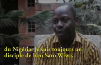 Un jeune homme en chemise rayée parle à quelqu’un hors caméra.