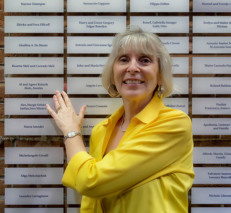 Une femme porte un haut jaune et pointe une plaque sur le mur d’honneur de Sobey.