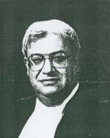 Photo en noir et blanc du jeune homme, il porte des lunettes.