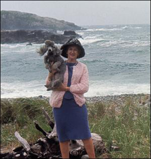 Une jeune femme avec un chien se tient sur le rivage de la mer.