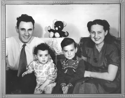 Homme et femme et deux enfants assis entre eux, un ours en peluche derrière.