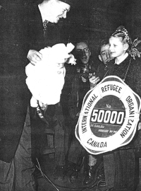 Ausma acceptant une poupée et un écriteau indiquant qu’elle est la 50 000e réfugiée.