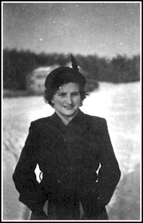 Jeune femme portant un manteau et un chapeau d’hiver, debout dans la neige.