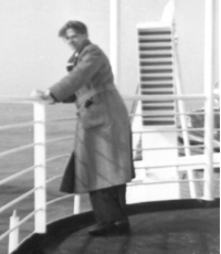 Bernardus en imperméable, appuyé contre la balustrade d’un bateau.