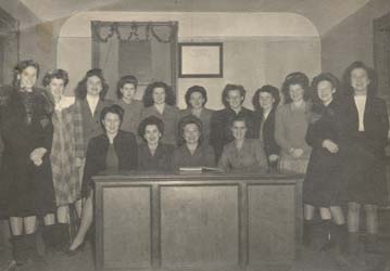 Plusieurs jeunes femmes assises et debout derrière un bureau.