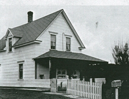 Maison blanche avec clôture et boîte aux lettres.