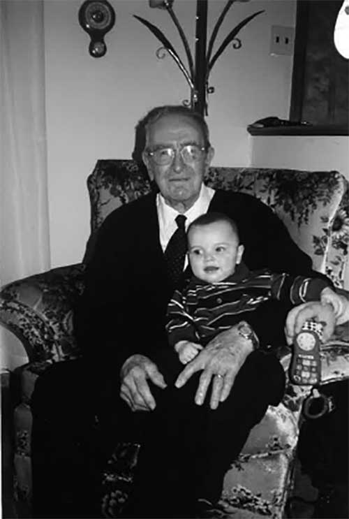 Un homme assis dans un fauteuil avec un bébé sur les genoux.