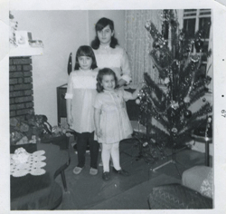 Trois jeunes filles debout près d’un arbre de Noël.