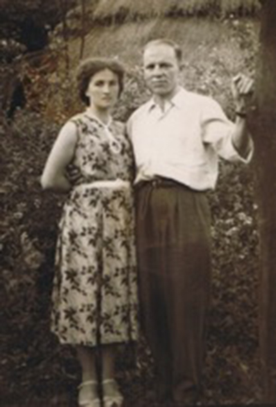 Un jeune couple se tient devant des buissons alors qu’ils se font photographier.