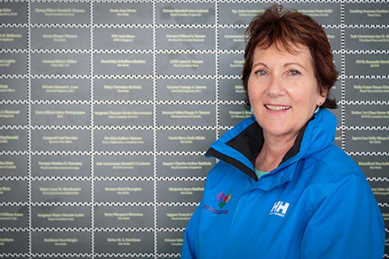 Le sourire de la femme dans la veste bleue y est debout devant un mur avec des plaques vertes