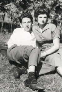 Homme et femme allongés sur la pelouse, avec des buissons derrière.