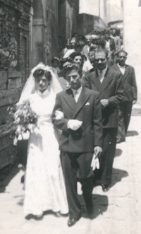 Procession nuptiale marchant dans une rue étroite avec les mariés menant.