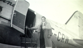 Giovanni en pardessus montant à bord d’un avion.