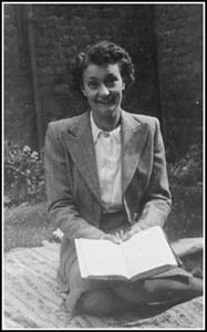 Femme agenouillée sur une couverture de pique-nique avec un livre ouvert dans les mains.