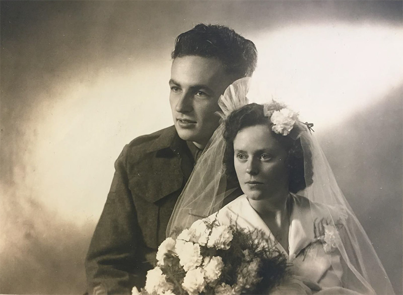 Un marié porte un uniforme et la mariée porte une robe de mariée et tient des fleurs.