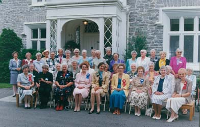 Photographie couleur récente d’un groupe de femmes, assises et debout, à l’extérieur d’un immeuble.