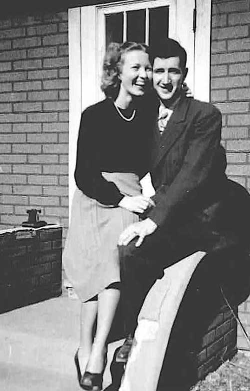 Une jeune femme qui rit est assise sur les genoux d’un jeune homme.