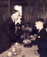 Jeune garçon serrant la main d’un monsieur plus âgé avec d’autres personnes applaudissant.
