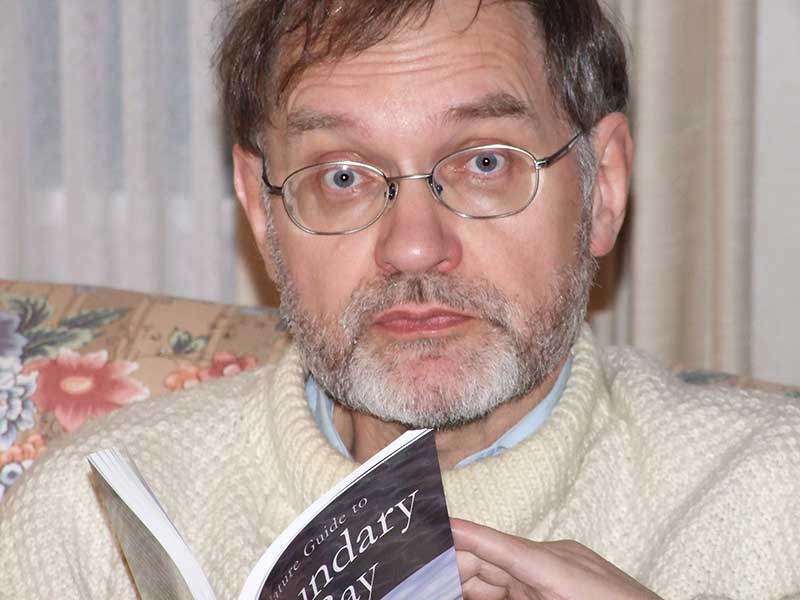 Homme portant verres, lisant un livre.