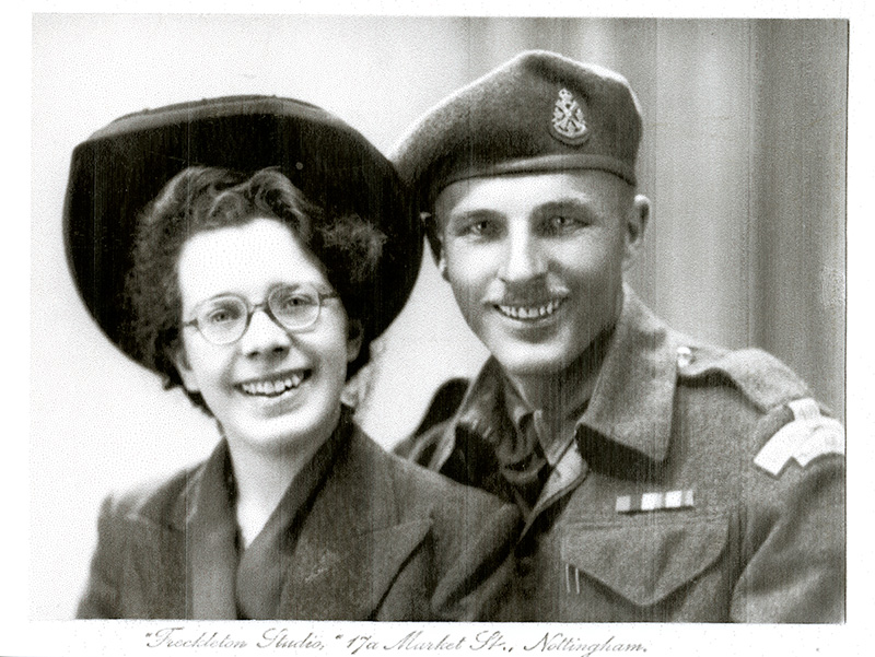 Belle dame bien habillée et bel homme portant l’uniforme militaire assis à côté de l’autre.