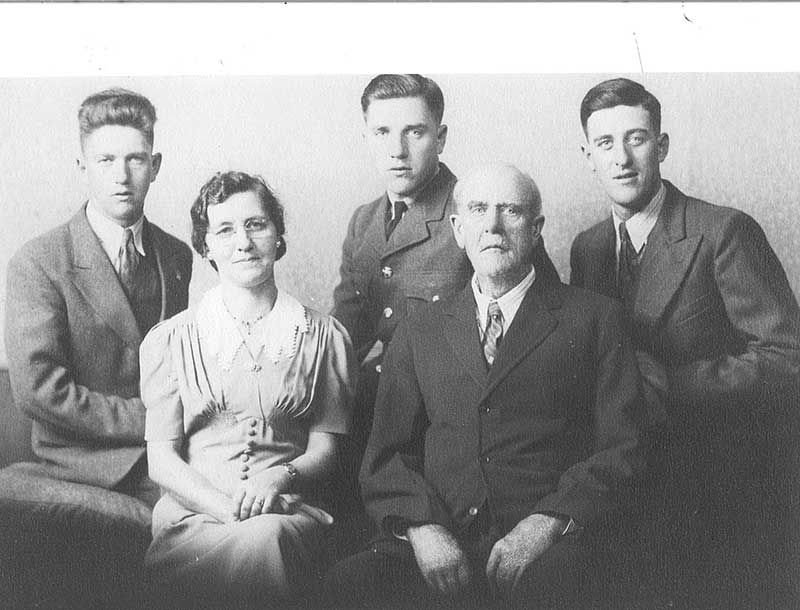 Un homme et une femme sont assis pour la photo. Trois jeunes hommes sont assis derrière eux.
