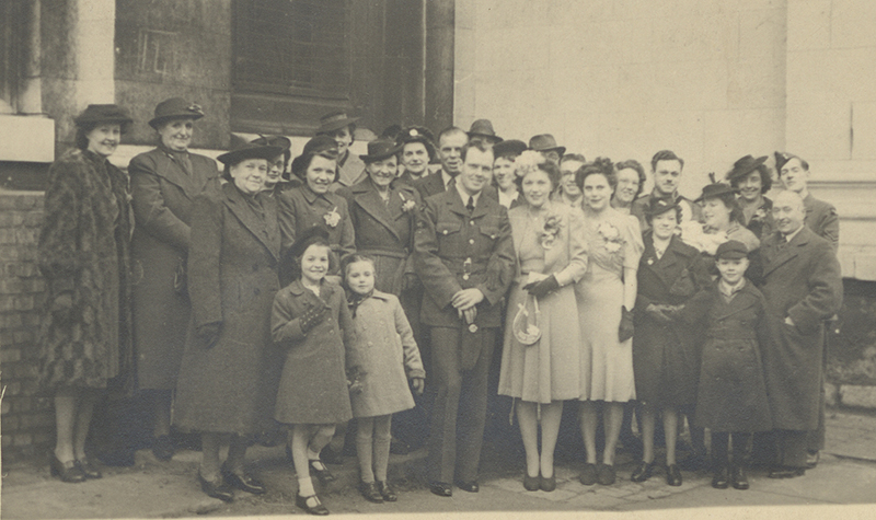 La photo de mariage de Grace et Arnold, avec leurs amis et leur famille debout avec eux.