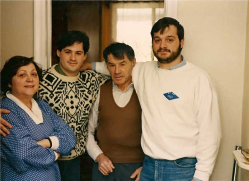 Une famille pose à l’intérieur de leur maison; mère, fils cadet, père, fils aîné.