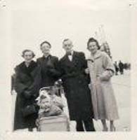 Vieille photographie de famille de quatre adultes, un bébé dans un landau.