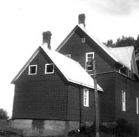Maison de ferme de couleur foncée.