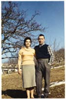 Homme et femme debout sur un chemin de terre devant un arbre.  