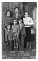 Photographie en pied de trois adultes et de trois enfants posant devant une aire délimitée par un rideau.
