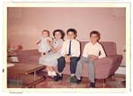 Petite photographie couleur d’une mère assise sur un divan rose avec trois enfants.