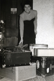 Sadie comme une jeune femme entourée de malles à bagages et de valises.