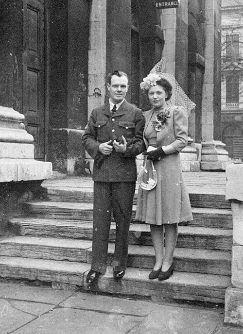 Un homme et une femme debout sur les marches d’une église en vêtements de mariage.