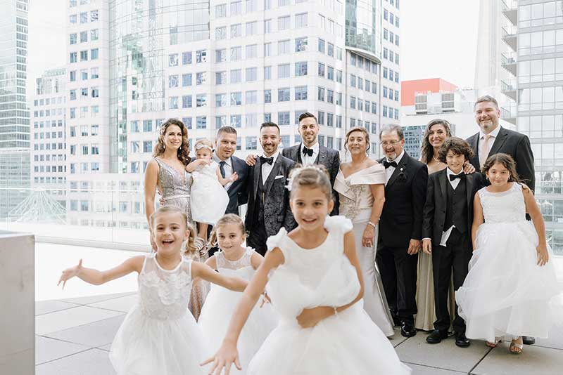 Les petites filles en blanc courent vers la caméra tandis que les adultes regardent en arrière-plan.