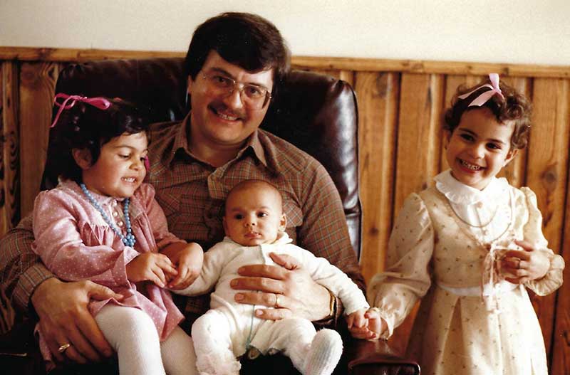 Un homme est assis avec trois enfants devant lui.
