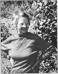 Je suis une femme plus âgée, debout devant un buisson.