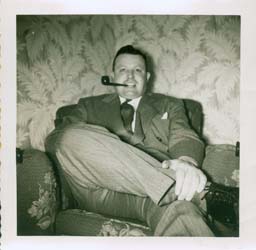 Le jeune Gerald assis sur un divan, fumant la pipe.