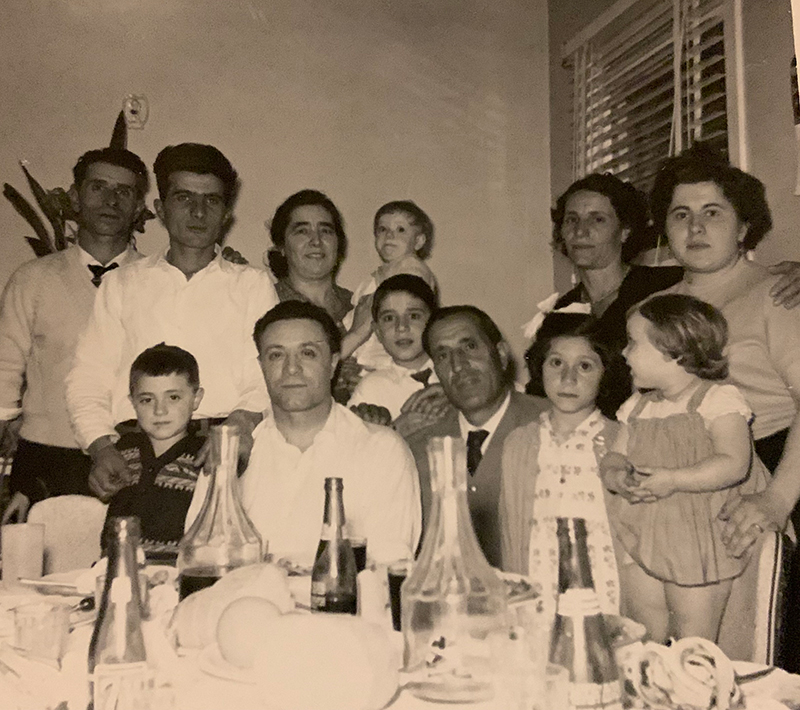 Un grand groupe de personnes derrière une table chargée de nourriture et de boissons.