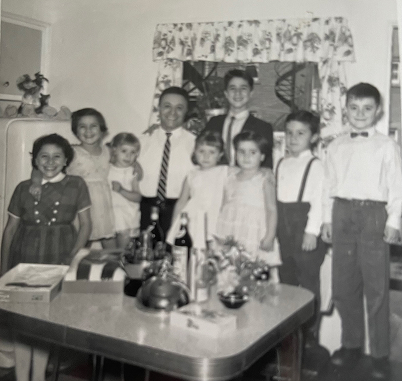 Un homme est entouré de huit enfants, tous bien habillés.
