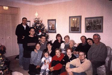 Plusieurs membres de la famille assis autour du divan du salon pendant le temps des fêtes.
