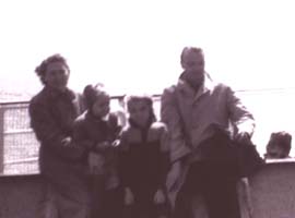 Une mère, un père et leurs deux enfants appuyés contre la balustrade du bateau.