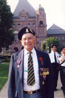 Henry est un homme âgé avec des médailles militaires sur sa veste et des épingles sur son béret.
